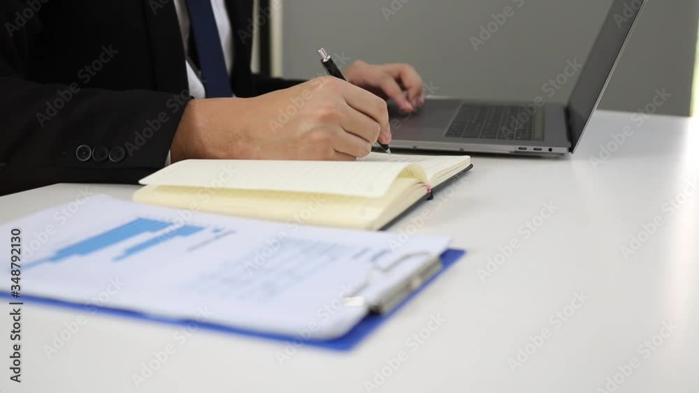 Manager notes the financial data summarized on the laptop computer in his notebook before meeting with the management. Manager notes the financial data summarized on the laptop computer in his notebook before meeting with the management.