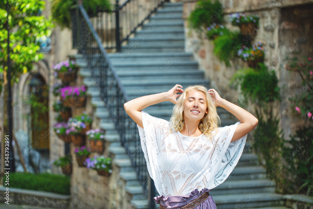 Woman adult young beautiful and happy blonde on the background of stairs on the street of a European city Woman adult young beautiful and happy blonde on the background of stairs on the street of a European city