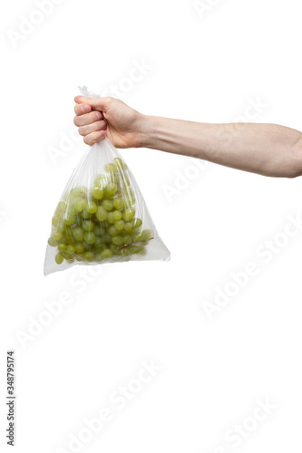 polythene bag held in hand isolated on white. man holding packet with bunch of fresh grape. delivery from shop to home. food supplies, donation, volunteer. product ingredients for dish, cooking meals