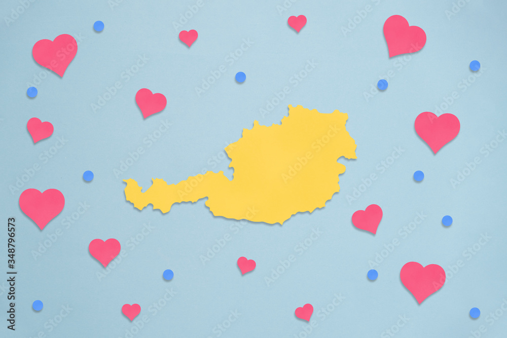 Gelbe Österreich-Landkarte mit Herzen und Konfetti auf blauem Hintergrund