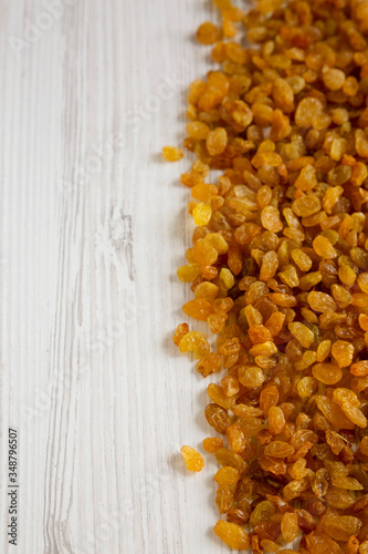 Dry Golden Raisins on a white wooden background, low angle view. Copy space.