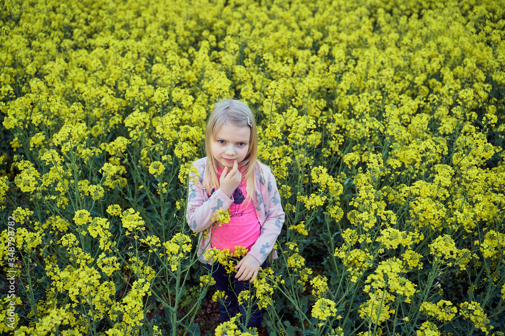 Fototapeta premium young girl in a rapeseed field in the spring evening