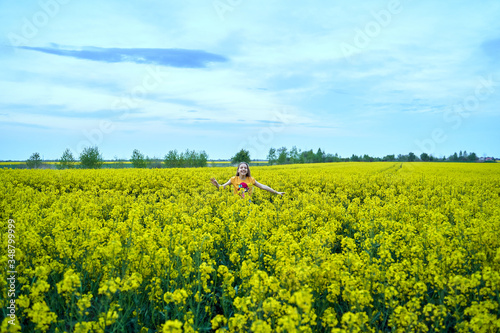 young girl in a rapeseed field in the spring evening