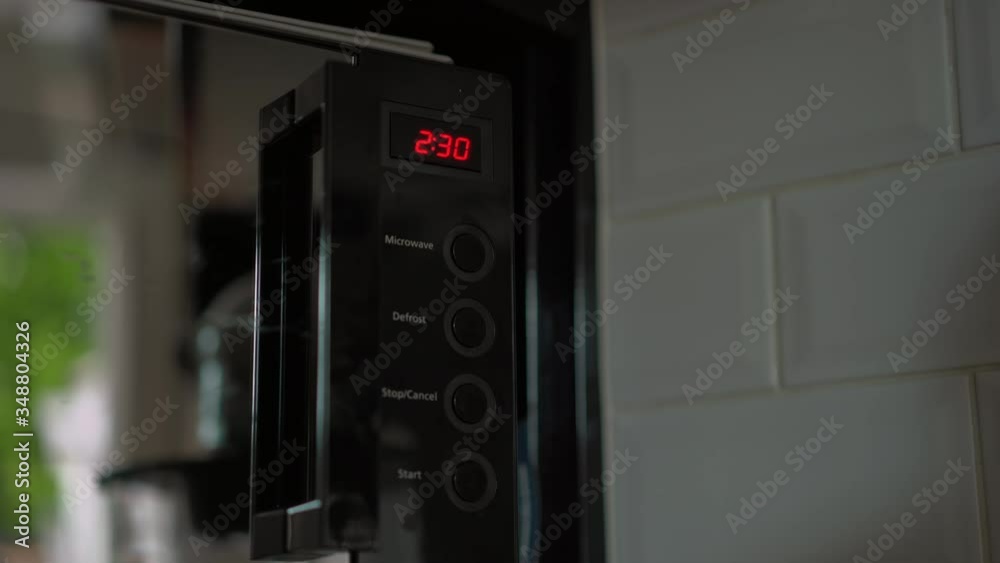 Microwave timer set for two minutes thirty seconds by male hand count down Microwave timer set for two minutes thirty seconds by male hand count down