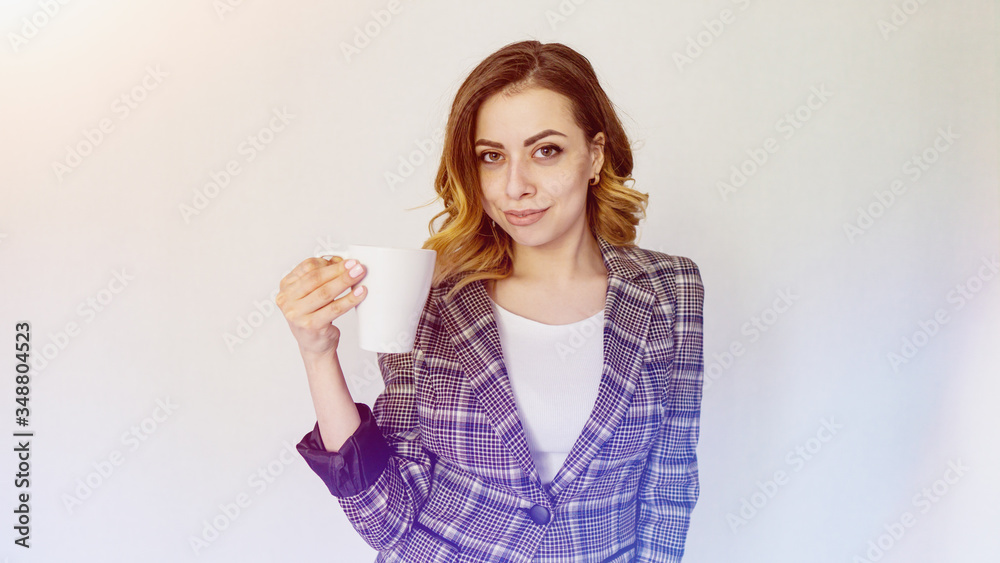 happy girl is standing with a cup of coffee and looking at the camera. beautiful girl in a checkered jacket is drinking coffee happy girl is standing with a cup of coffee and looking at the camera. beautiful girl in a checkered jacket is drinking coffee