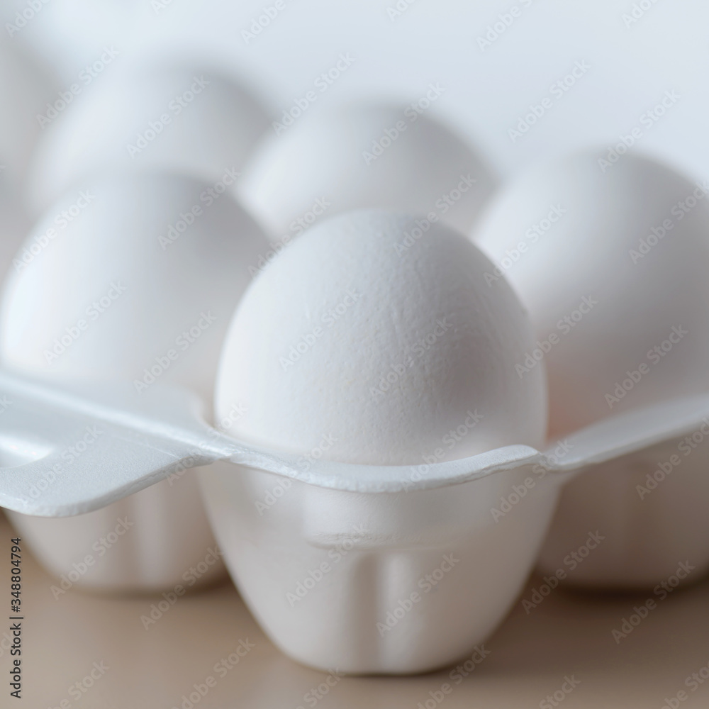 White raw chicken eggs in a plastic tray close-up. Chicken eggs background. White raw chicken eggs in a plastic tray close-up. Chicken eggs background.