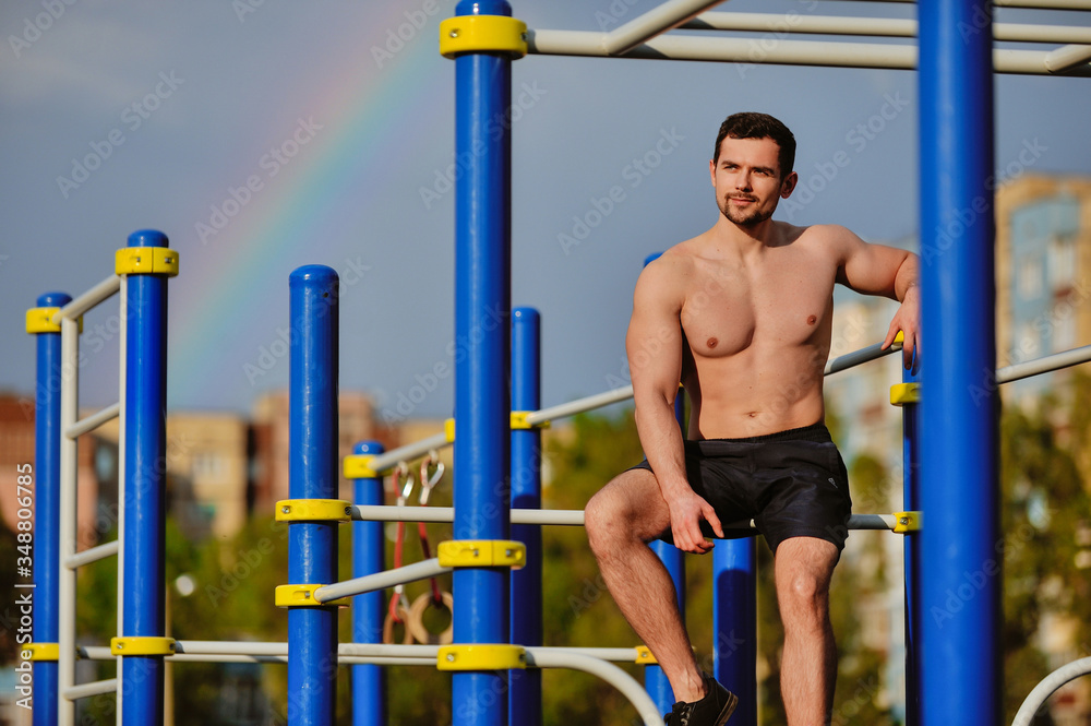 Fototapeta premium Young strong guy pulls himself up on the horizontal bar.