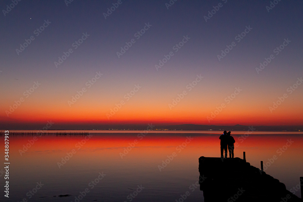 Couple making pictures with the cell phone of the sunset in Albufera, a lake near Valencia
