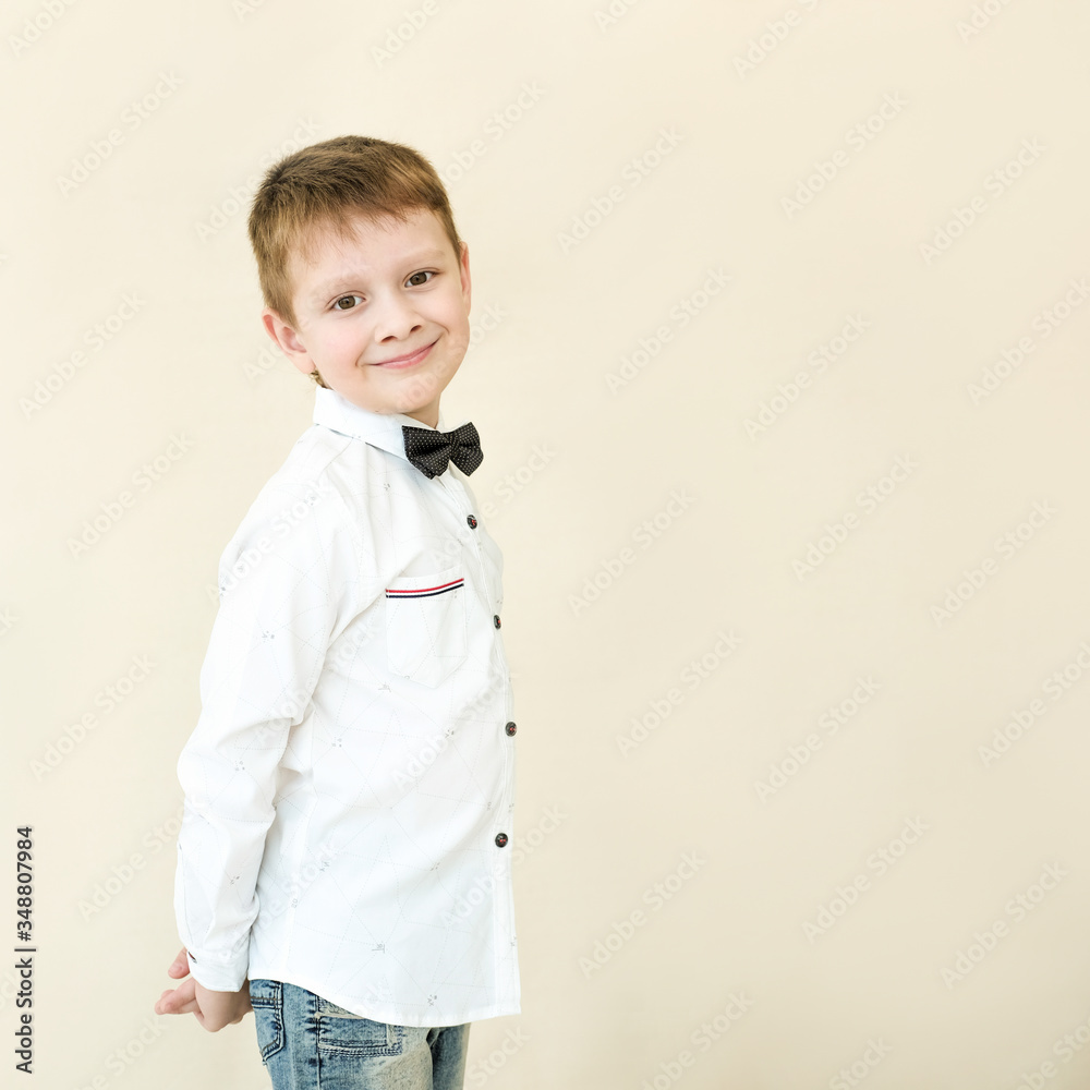 portrait of a little boy in a white shirt and hat. He is smiling. On a beige background. Holiday concept portrait of a little boy in a white shirt and hat. He is smiling. On a beige background. Holiday concept