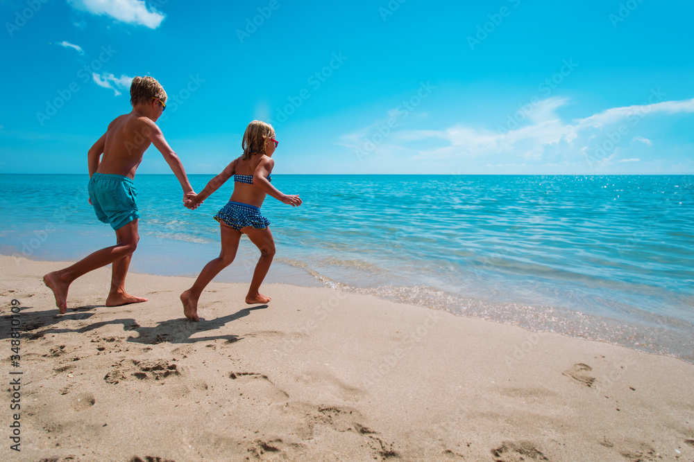happy boy and girl run to swim on beach