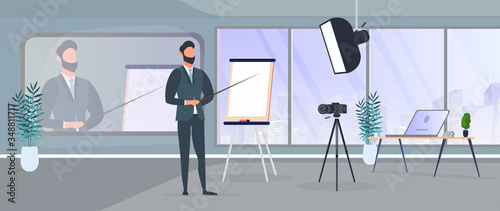 A man in a business suit with a tie is giving a presentation to the camera. The teacher is writing a lesson. The concept of blogging, online training and conferences. Camera on a tripod, softbox. 