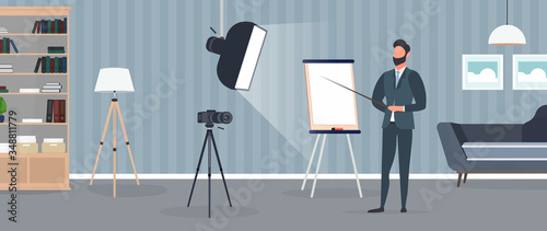 A man in a business suit with a tie is giving a presentation to the camera. The teacher is writing a lesson. The concept of blogging, online training and conferences. Camera on a tripod, softbox. 