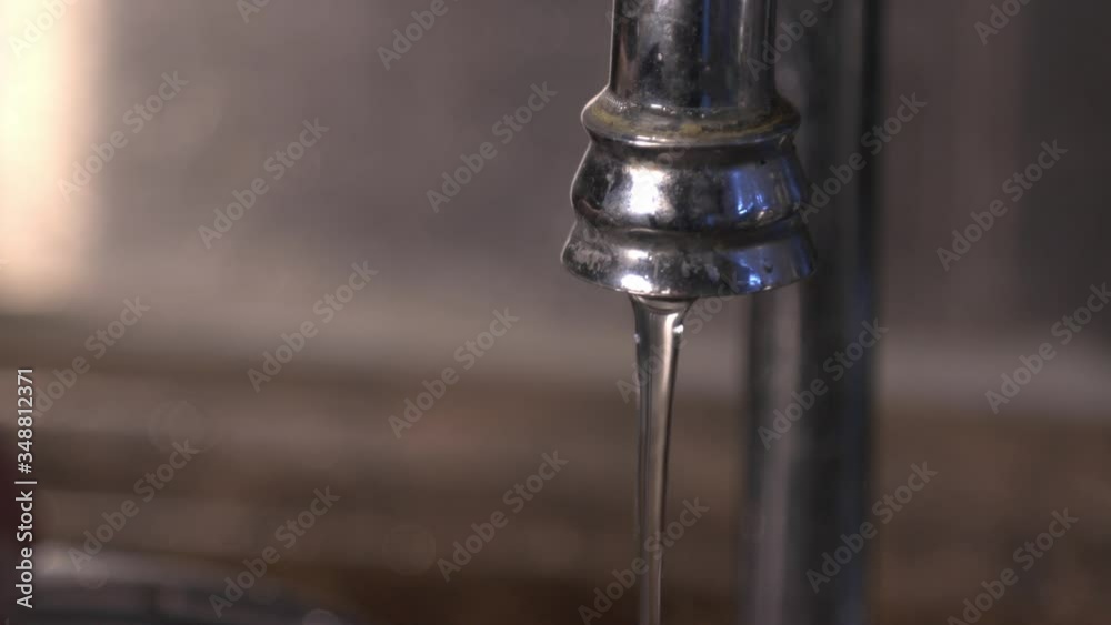 Water Flowing From The Stainless Faucet Into The Sink.- close up shot Water Flowing From The Stainless Faucet Into The Sink.- close up shot