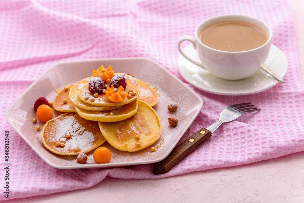 homemade pancakes with raspberries, physalis, powdered sugar on pink napkin with Cup of tea or coffee homemade pancakes with raspberries, physalis, powdered sugar on pink napkin with Cup of tea or coffee