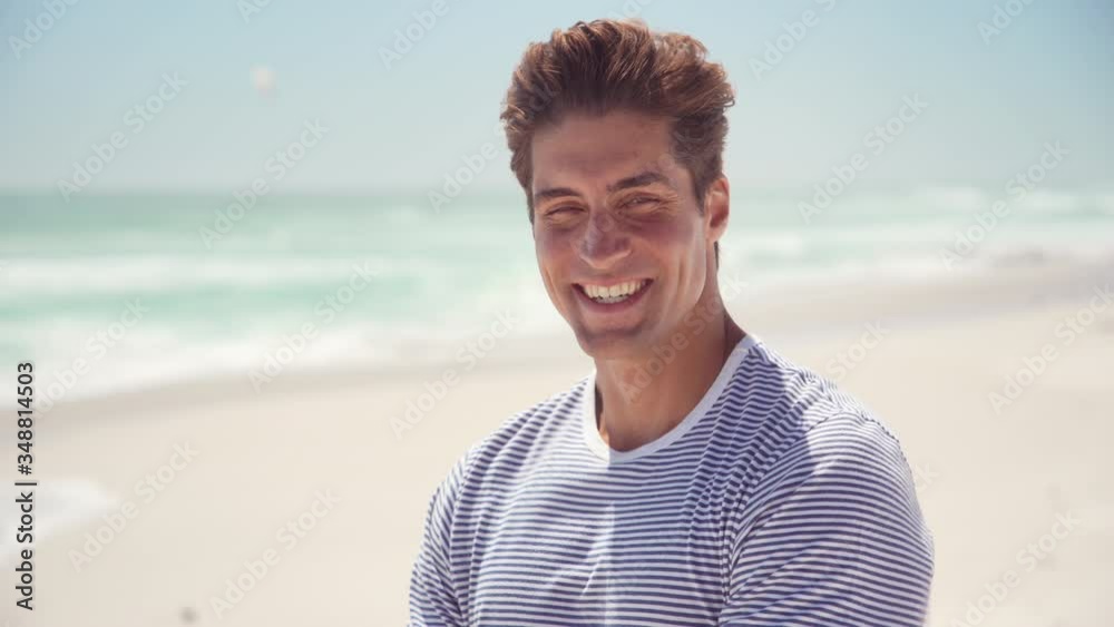 Portrait of handsome young man wearing sunglasses and looking at camera. Portrait of joyful man enjoying summer holiday at beach. Young casual man in shades with big grin and copy space.