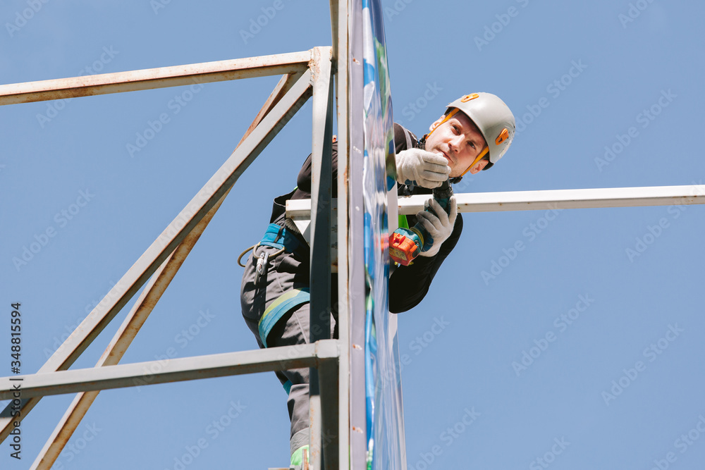 Industrial climber in helmet and overall working on height. Risky job. Professional worker