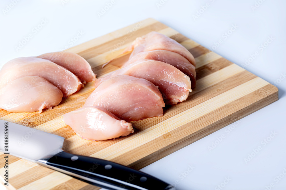 Raw meat chicken breast cut into pieces. Pieces of chicken meat on a Board on a white background.