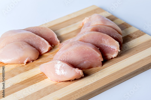 Raw meat chicken breast cut into pieces. Pieces of chicken meat on a Board on a white background.
