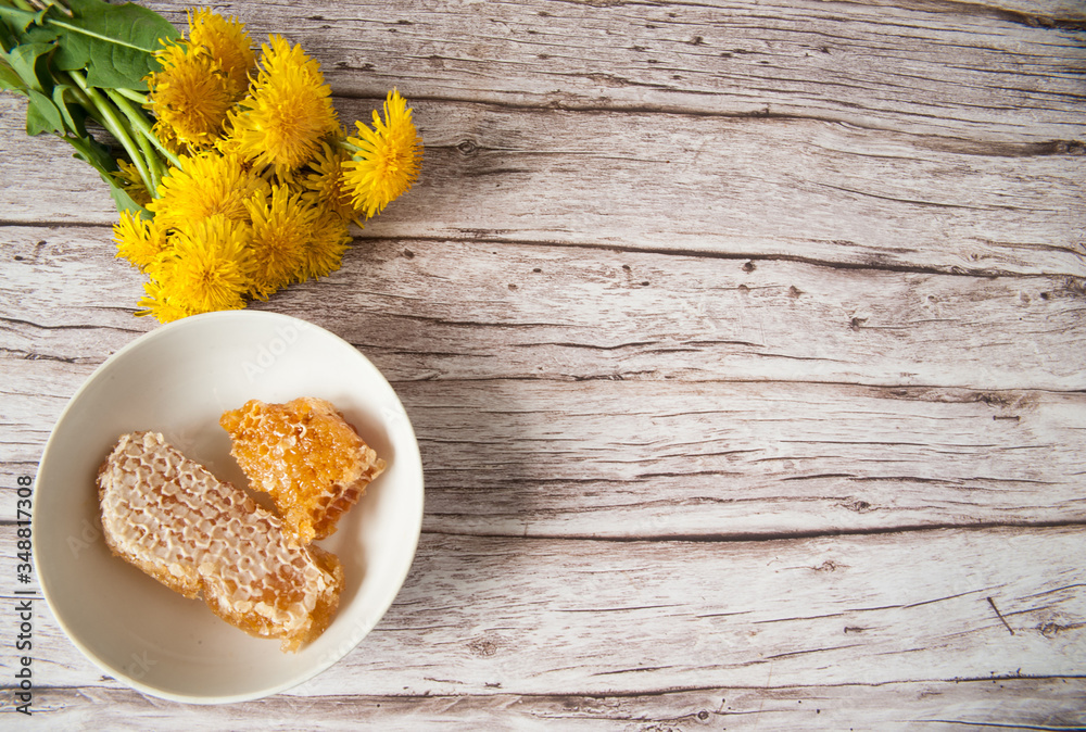 A bouquet of yellow dandelion flowers and a Cup with honey combs on a wooden background. Alternative medicine, medicinal herbs. Selective focus. Free space.