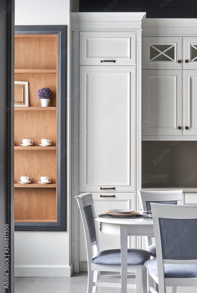 Fototapeta premium Italian kitchen in classic style with white painted facades with a dining table for 4 people