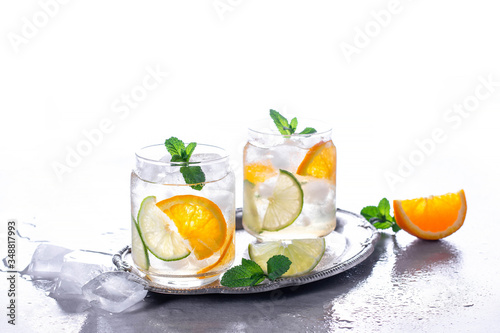 Cold drinks with ice and mint. Orange cocktail on gray concrete background