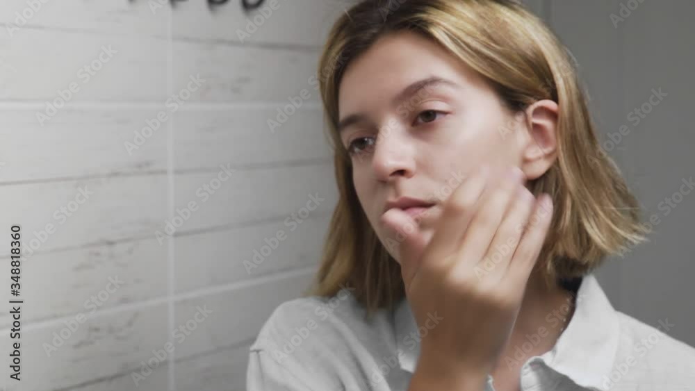 Young woman applying cream and looking in mirror enjoy natural beauty and healthy Young woman applying cream and looking in mirror enjoy natural beauty and healthy