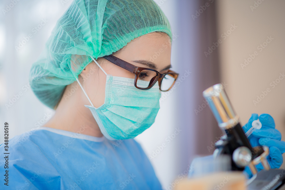 Asian Young woman scientist looking through a microscope in a ...