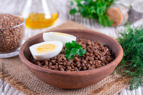 Boiled lentils with egg in ceramic bowls on a wooden background