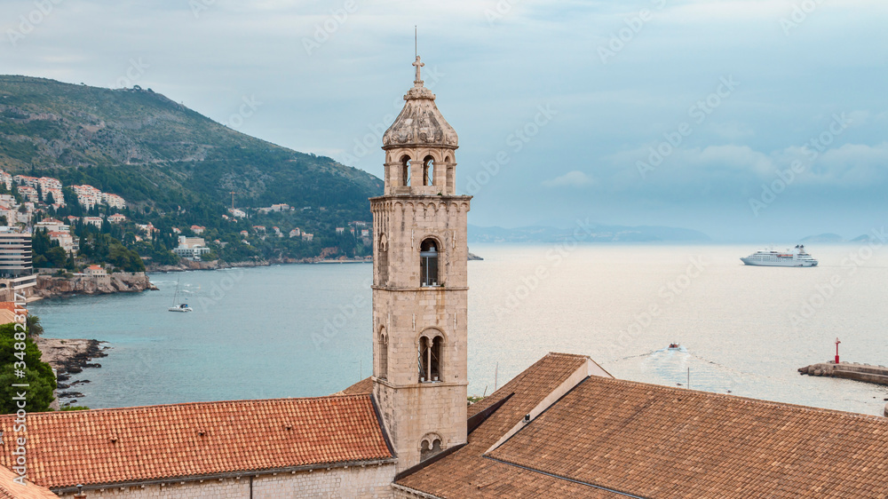 view of the watchtower and tiled roofs of the ancient Croatian city of Dubrovnik against the background of the sea and cloudy sky