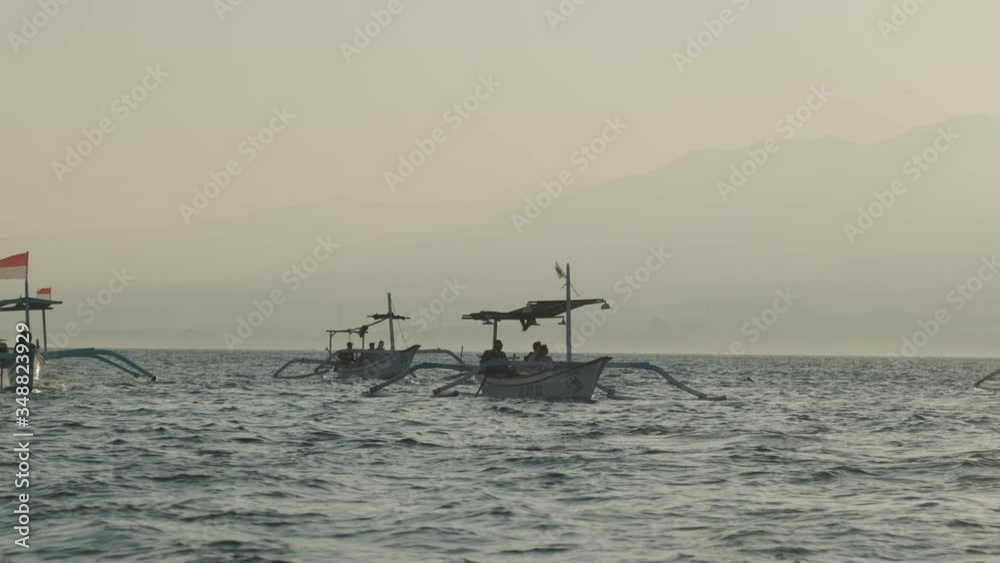 Asian white double-outrigger boats in blue waters. Windy weather Asian white double-outrigger boats in blue waters. Windy weather