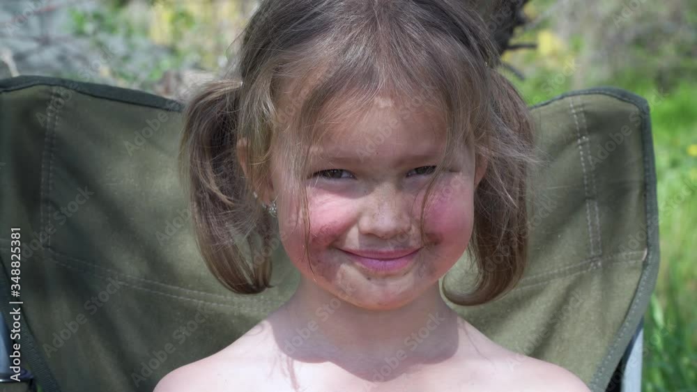 Portrait of smiling and grimy little girl. Tiny kid have fun, enjoy nature outdoors. 4K