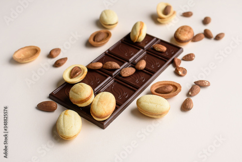 A bar of chocolate lies on a light background with almonds, walnuts, nuts with boiled condensed milk. View from above, place for text. Flat lay