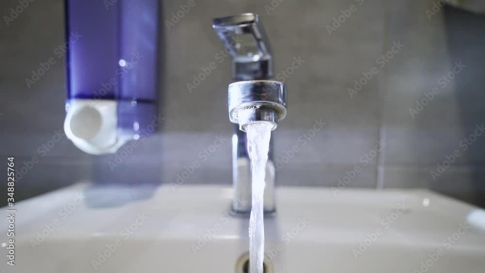 Hot tap water. Warm water flows from the tap in the bathroom. Coronavirus travel prevention washing hands with soap and hot water. Hand hygiene for coronavirus outbreak. Protection by washing hands.