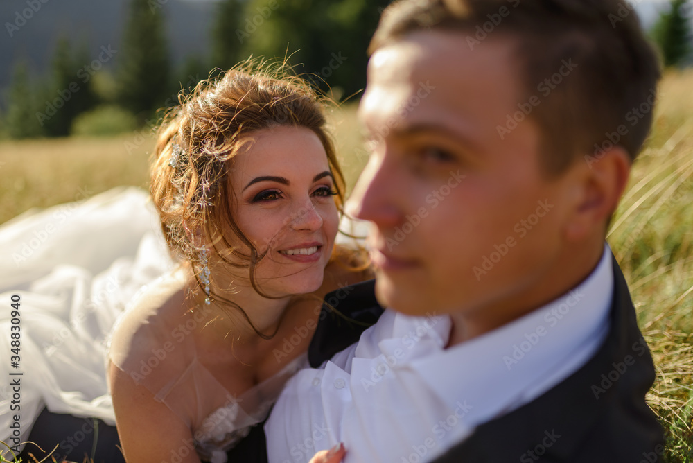 Wedding photography in the mountains. Newlyweds are lying in the grass. The couple is smiling. Close-up. Wedding photography in the mountains. Newlyweds are lying in the grass. The couple is smiling. Close-up.