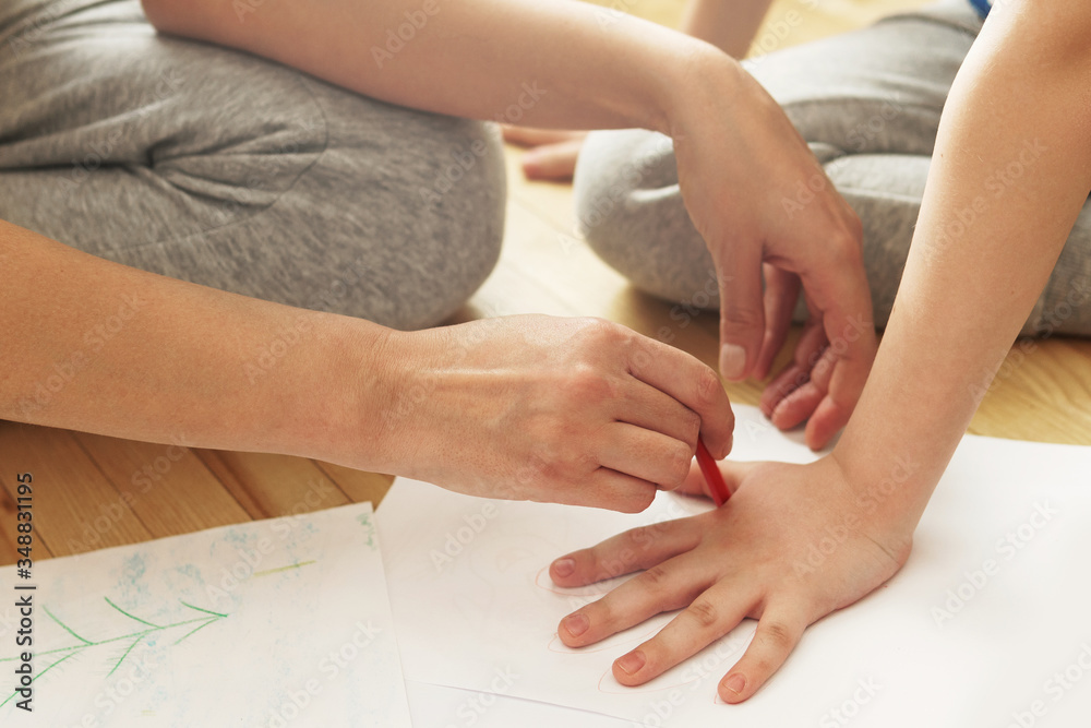 Mother is drawing outline of her son's palm Mother is drawing outline of her son's palm
