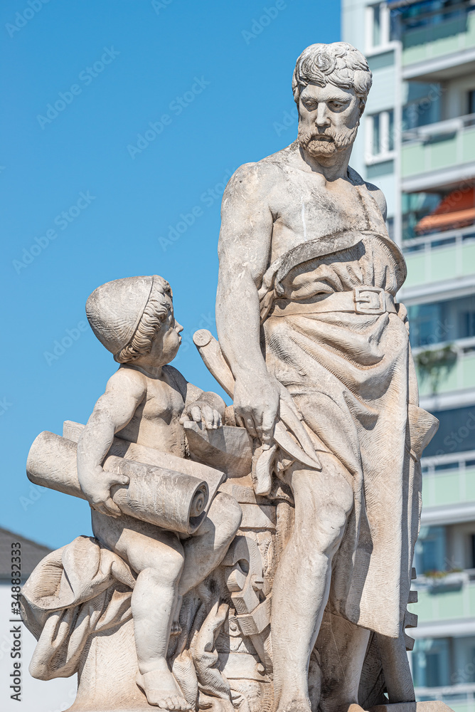 Elderly and young – old sculpture of engineer and his scholar on Zoll Bridge in Magdeburg downtown at blue sky background, Germany, details, closeup