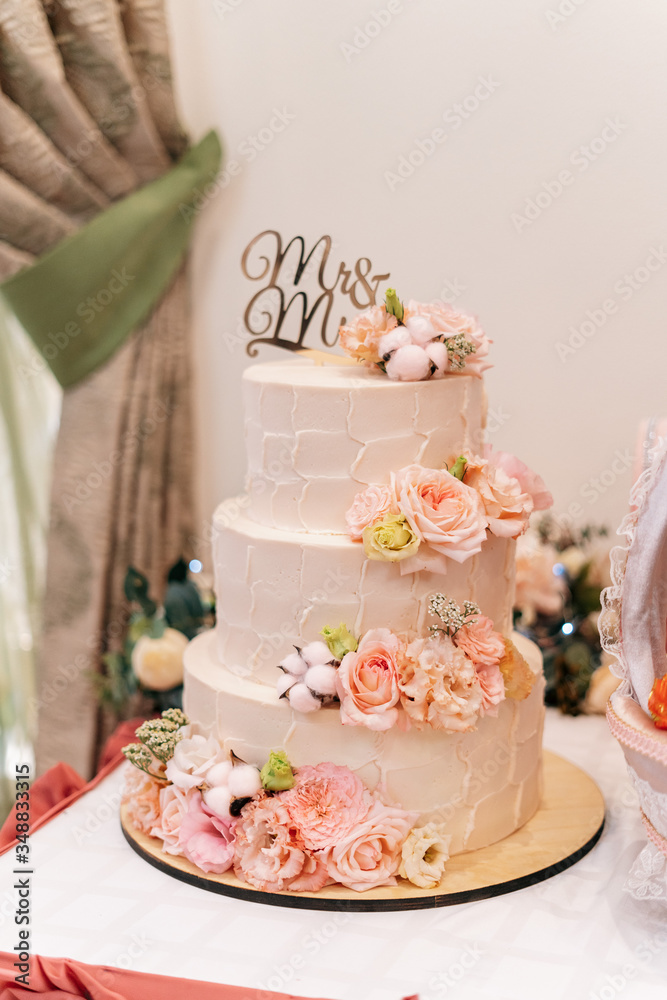 Three-tier wedding cake nested with flowers and roses Three-tier wedding cake nested with flowers and roses