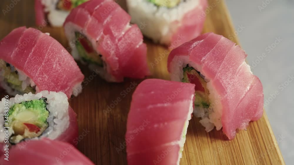Sushi roll set on a wooden board. Various Sushi japanese food in restaurant. Rotated California set tuna wrapped, flying fish roe. Sushi roll set on a wooden board. Various Sushi japanese food in restaurant. Rotated California set tuna wrapped, flying fish roe.