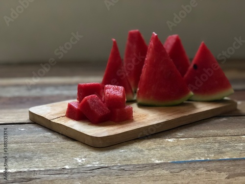 Fresh Watermelon on wood plank,sliced with triangle like christmas tree,dimly light,selective focus.Fruit for summer time.