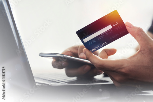 User Filling information on the back of credit card. With mobile phone for online shopping  E-payment technology, or mobile phone financial application concept, copy space, credit card mockup