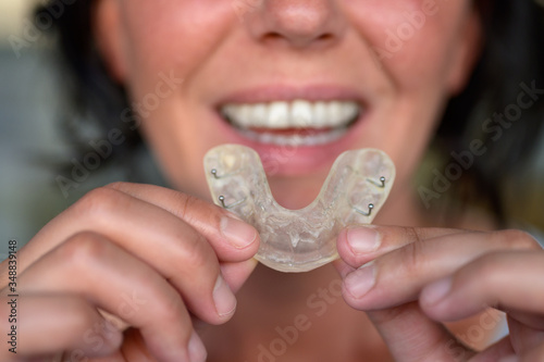 Woman suffering from bruxism holding up a guard