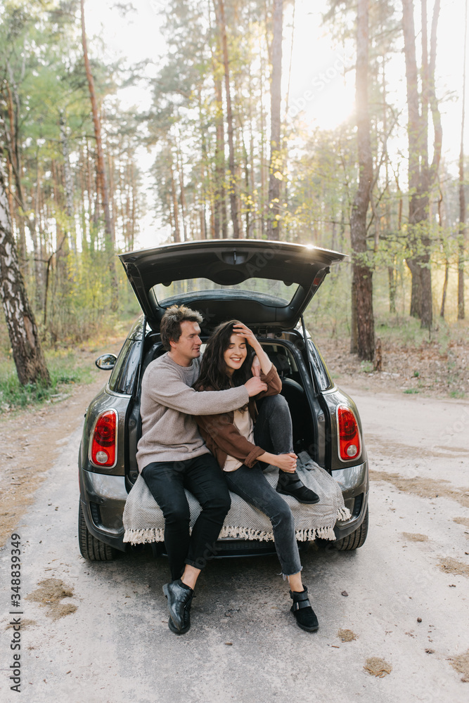 Young beautiful couple relaxing together sitting on a car trunk Young beautiful couple relaxing together sitting on a car trunk