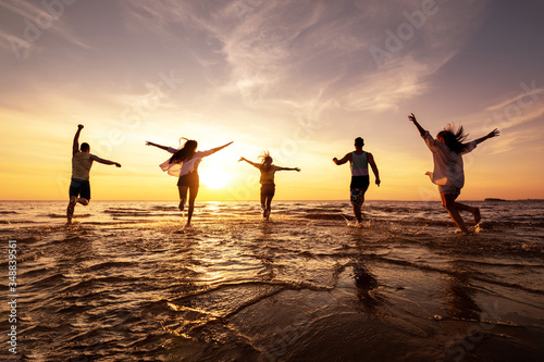 Valokuva Five happy friends runs at sunset beach
