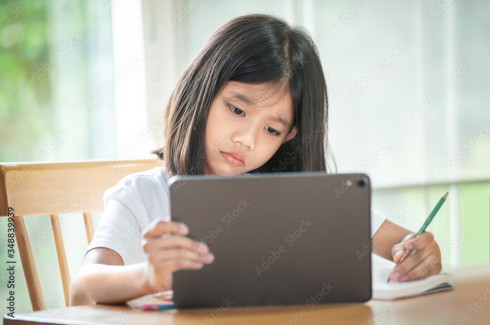 Asian girl is studying online at home with tablet Showing a face do not understand the teaching and learning content Asian girl is studying online at home with tablet Showing a face do not understand the teaching and learning content