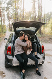 Young beautiful couple relaxing together sitting on a car trunk