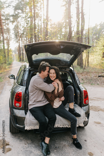 Young beautiful couple relaxing together sitting on a car trunk