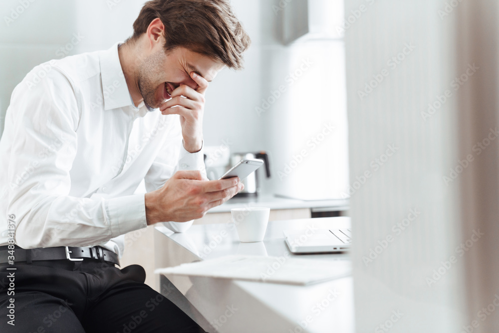 Photo of joyful bristle businessman laughing and using mobile phone