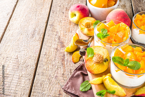 Curd or yogurt dessert with canned and fresh peaches, on wooden rustc background. Summer breakfast fruit dessert. photo