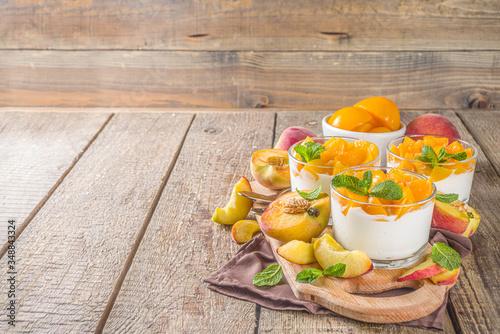 Curd or yogurt dessert with canned and fresh peaches, on wooden rustc background. Summer breakfast fruit dessert.