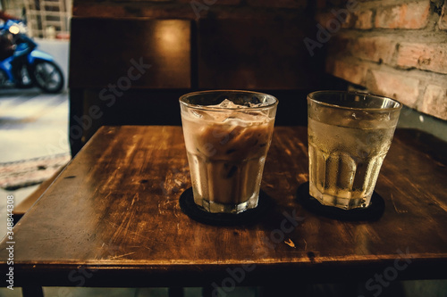 Vietnamese Milk Coffee on Wooden Table. Traditional Hot Drinks in Vietnam. Close-up Vietnamese Drip Coffee and Ice mug served with milk, Iced black coffee.